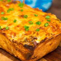 a cheesy casserole with green onions on top is sitting on a cutting board