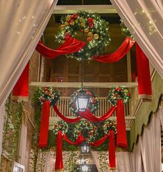 an archway decorated for christmas with red ribbon and wreaths hanging from it's sides