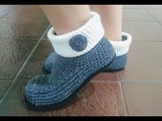 a child's feet wearing blue and white crocheted slippers on the floor