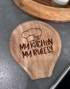 a wooden cutting board with the words my kitchen my rules on it