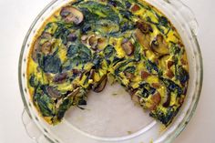 a quiche with spinach and mushrooms in a glass dish