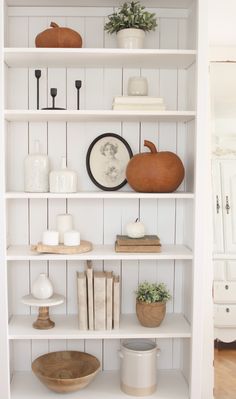 a white book shelf filled with books and vases