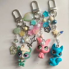 littlest pet shop keychains are lined up on a white surface with charms attached to them