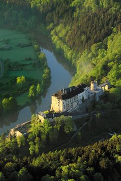 an aerial view of a castle in the middle of a green valley surrounded by trees