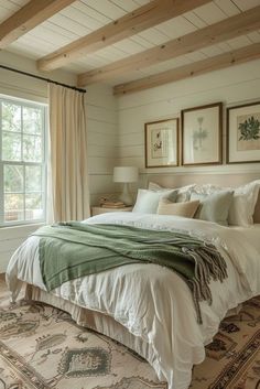 a large bed sitting in a bedroom next to a window covered in blankets and pillows