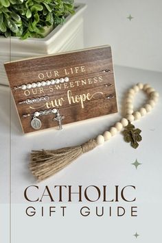 the catholic gift guide is on display next to a potted plant and rosary beads