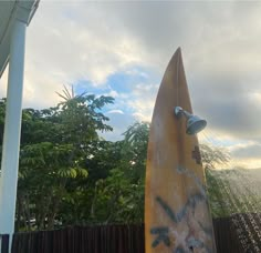 a surfboard with spray painted on it next to a wooden fence and some trees