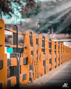 an orange and black fence that is next to a road with trees in the background