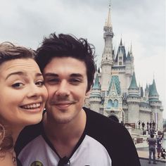 a man and woman taking a selfie in front of a castle at disney world