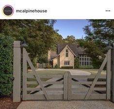 an image of a house with a gate in the foreground and trees behind it