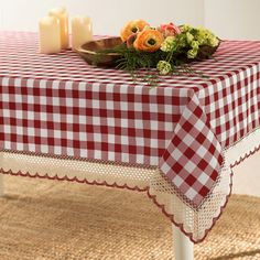 a red and white checkered tablecloth with flowers on it next to two candles