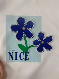 two blue flowers on a white background with the words nice written in gold and diamonds