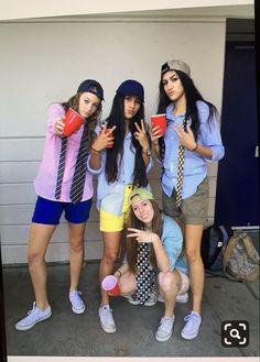 four young women posing for a photo in front of a garage door with coffee cups