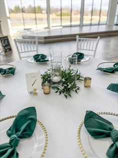 the table is set with green napkins and place settings for guests to sit at