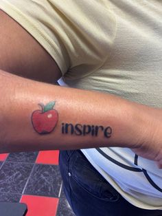 a person with a tattoo on their arm that says inspire and an apple in the middle