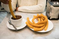 french fries on a plate next to a cup of coffee and a spoon with sauce