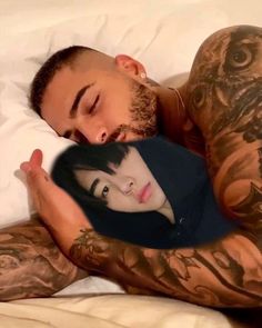 a man and woman laying in bed with tattoos on their arms