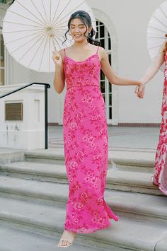 two women in pink dresses holding umbrellas on steps