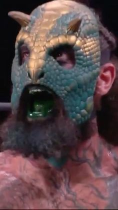 a man with a dragon mask on his face and beard is looking at the camera