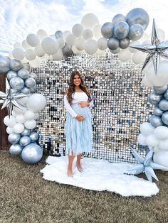 a pregnant woman standing in front of an arch made out of balloons