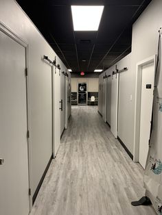 an empty hallway with white doors and gray walls