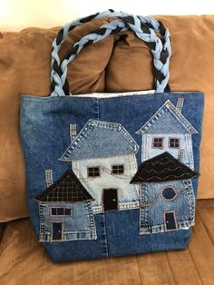 a denim bag with houses on it sitting on a couch