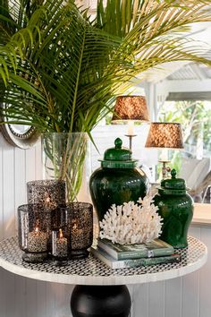 a table topped with green vases next to a palm tree and other decor items