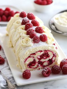 a cake roll with raspberries and cream frosting