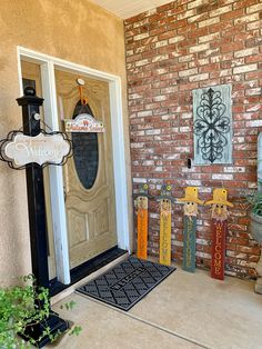 a welcome sign is on the front door of a house with brick walls and potted plants