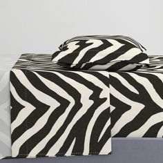 a bed with a zebra print comforter on top of it and pillows in the back