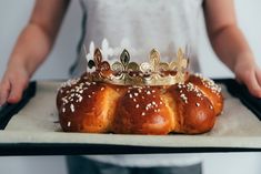 a person holding a tray with some breads and a crown on top of it