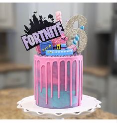 a pink and blue cake with the number six on it's top, sitting on a table