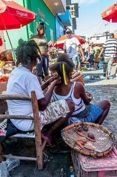 two people sitting on a bench in front of an open market