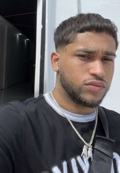 a man with a beard wearing a black t - shirt and silver chain around his neck