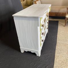 a white dresser sitting on top of a hard wood floor next to a black backdrop