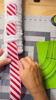 someone is making a candy cane decoration out of construction paper