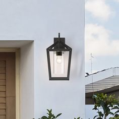 a light that is on the side of a building next to some plants and trees