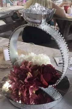 a table topped with a vase filled with flowers next to a mirror plate on top of it