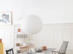 a dining room table with chairs and plates on it in front of a white wall