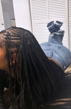 a woman with long black dreadlocks laying on top of a bed next to a pair of shoes