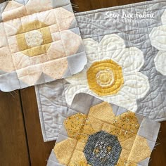 two quilted placemats sitting on top of a wooden table next to each other