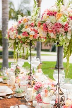 a long table is set with flowers and candles for an elegant wedding reception at the park