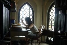 a woman sitting at a desk in front of a window with an open book on it