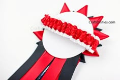 a red and black ribbon is attached to a white plate with scissors in it on a white surface