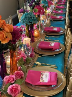 the table is set with pink, blue and gold place settings for an elegant dinner