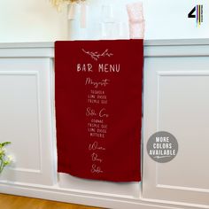 a red towel hanging on the side of a white wall next to a vase with flowers