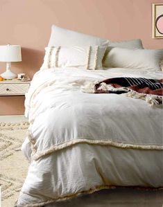 an unmade bed in a bedroom with pink walls and rugs on the floor