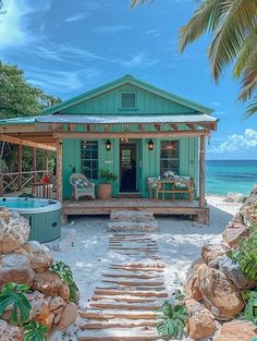 a house with a hot tub on the beach next to some rocks and palm trees