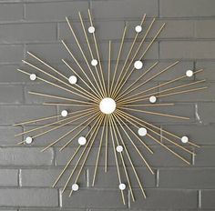 a sunburst made out of wood sticks on a brick wall with white balls