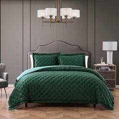 a bed with green comforter and pillows in a room next to a lamp on a table